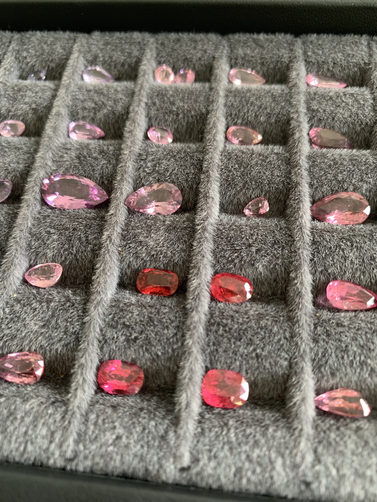A tray of natural Luc Yen spinels showing red, hot pink and peach tones