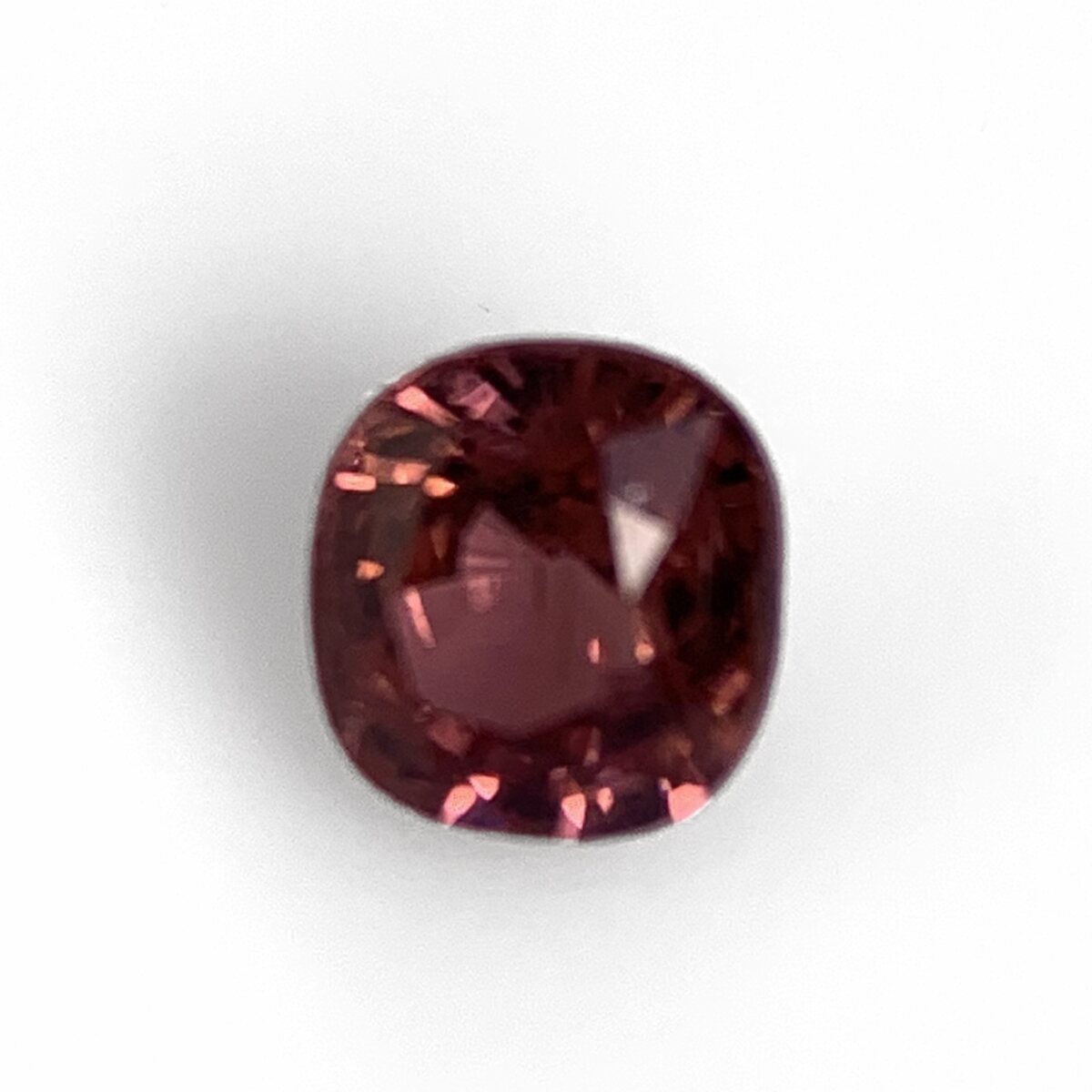 Brownish pink spinel 0.57 ct cushion, face up on white